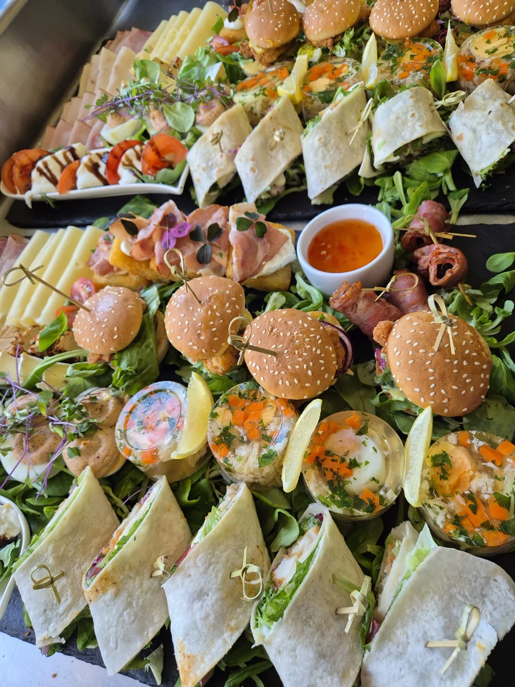 Deska przystawek Granicy Smaków: mini burgery, wrapy, wędliny i sałatki ułożone tematycznie